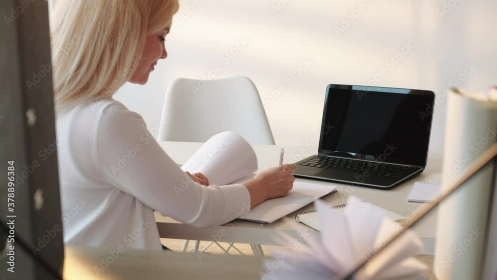 Online interview. Video conference. Cheerful female HR manager using laptop with empty black screen at cosy light home office. Zoom corporate call. COVID-19 pandemic. Social distancing. New normal. Online interview. Video conference. Cheerful female HR manager using laptop with empty black screen at cosy light home office. Zoom corporate call. COVID-19 pandemic. Social distancing. New normal.
