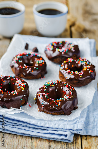 Baked chocolate doughnuts with chocolate glaze and multi color sprinkles