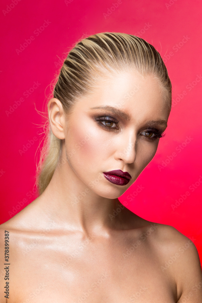 Fototapeta premium Frontal beauty portrait of young woman with perfect makeup over red background.