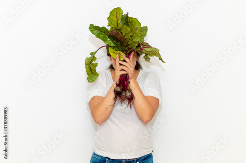 Real young man with a bunch of radishes covering his face. Isolated on a white background.