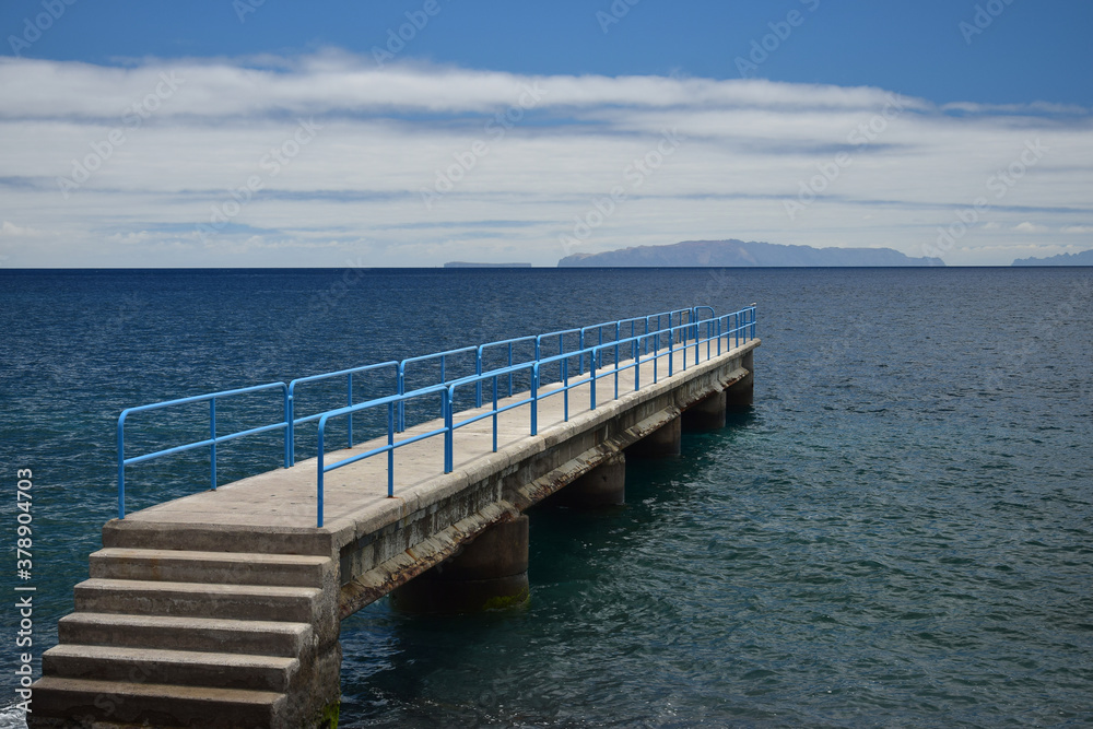 A little pier with a blue handrail at the coast of Santa Cruz, Madeira, Portugal.