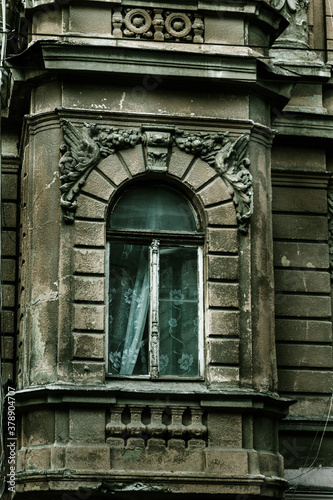 Mystical vintage cityscape. Old wooden windows of an obsolete vintage model on the wall of an old residential building. Wooden windows abandoned untrimmed residential old building