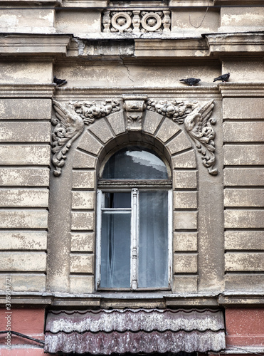 Mystical vintage cityscape. Old wooden windows of an obsolete vintage model on the wall of an old residential building. Wooden windows abandoned untrimmed residential old building
