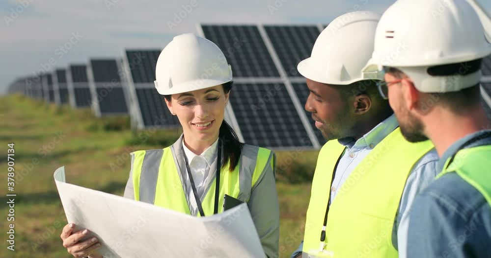 Three technical engineers review plan on paper and discuss. Two men listen to woman's explanations about nuances of work. Three technical engineers review plan on paper and discuss. Two men listen to woman's explanations about nuances of work.