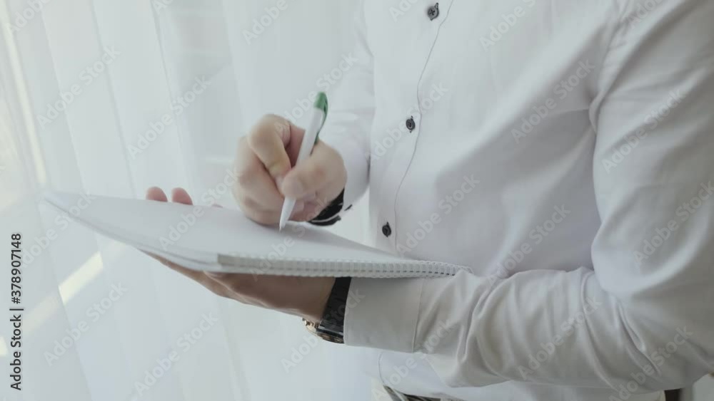 Close up of Young man worker taking notes standing in office. Close up of Young man worker taking notes standing in office.