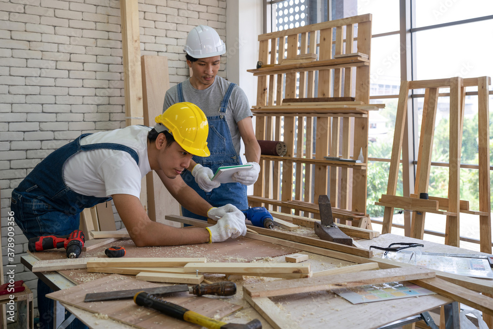 An Asian carpenter is drawing a line on a piece of wood, preparing to cut into sections. An Asian carpenter is drawing a line on a piece of wood, preparing to cut into sections.