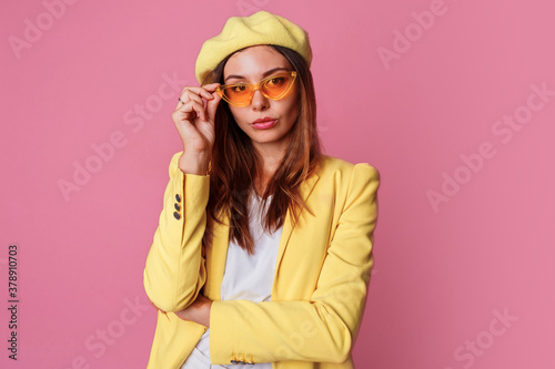 Graceful stylish woman in bright yellow clothes standing over pink background. Height fashion look.