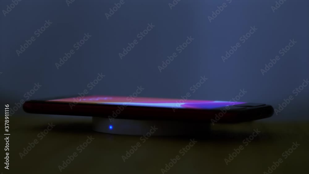 Wireless induction charger base for mobile phone. Moonlight scene while a smartphone is placed on the dock for charging. Wireless induction charger base for mobile phone. Moonlight scene while a smartphone is placed on the dock for charging.
