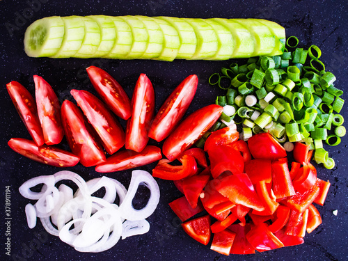 Fresh vegetables - cucumber, tomatoes, onion, chives and  bell pepper on black cutting board  © Jacek Chabraszewski