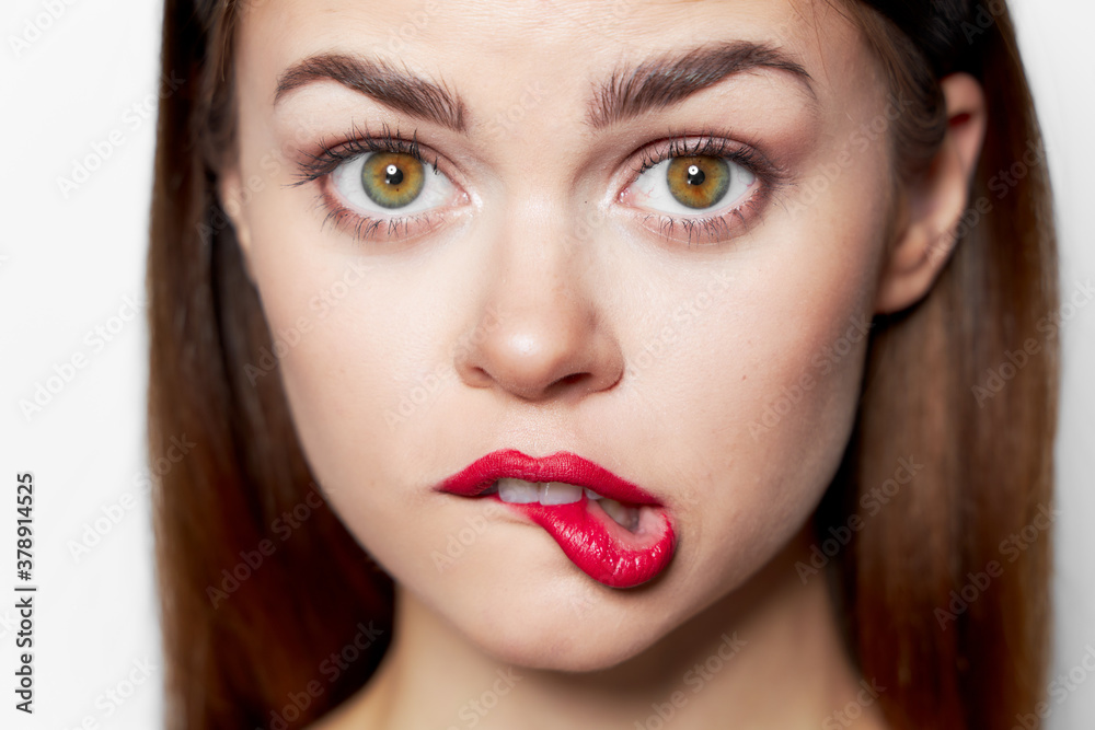 Beautiful woman face close-up red bites her lip Beautiful woman face close-up red bites her lip