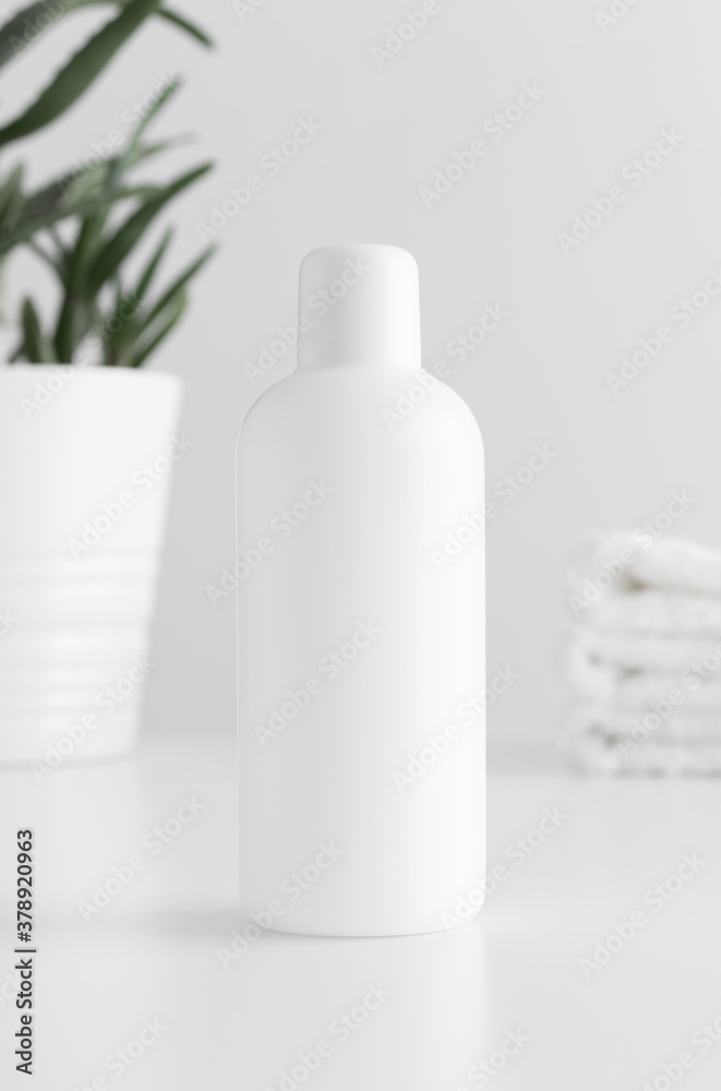 White cosmetic bottle mockup with a aloe vera and towels on a white table. White cosmetic bottle mockup with a aloe vera and towels on a white table.