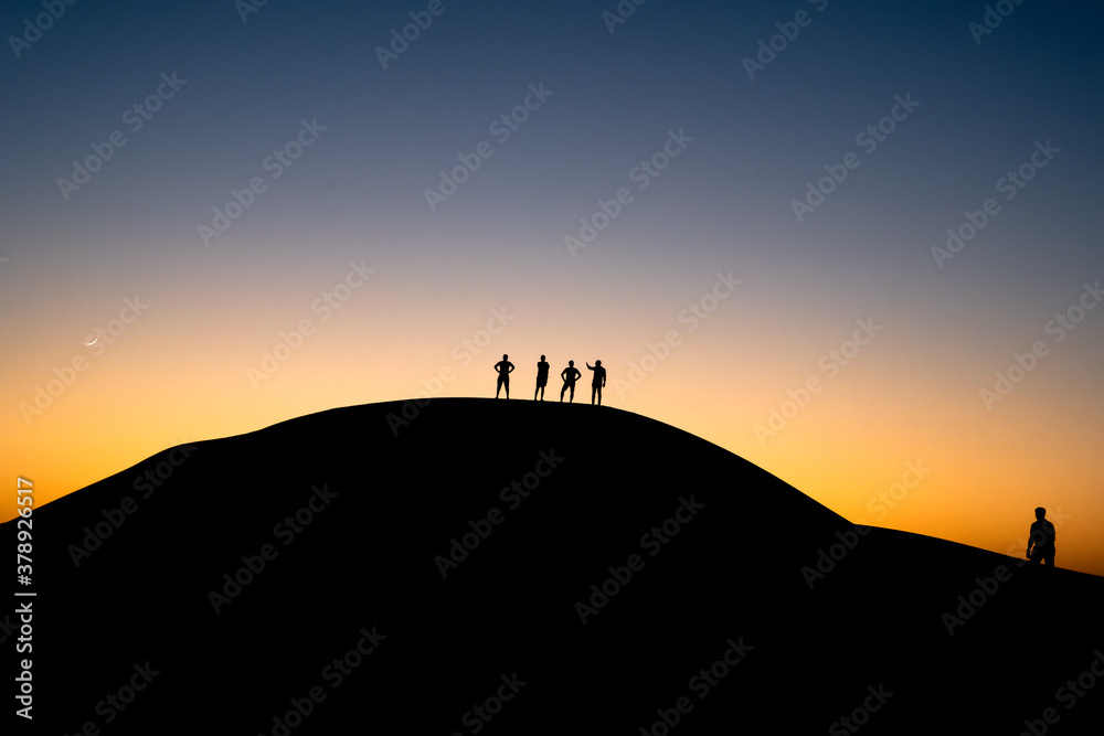silhouette of a person on a mountain top climbing in desert