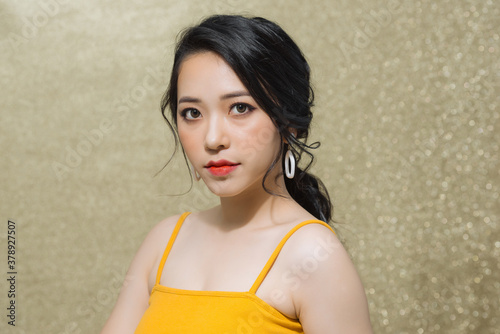 Portrait of attractive young Asian woman over gold background.