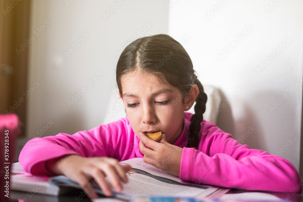 Little girl doing homework and eating cookie Little girl doing homework and eating cookie