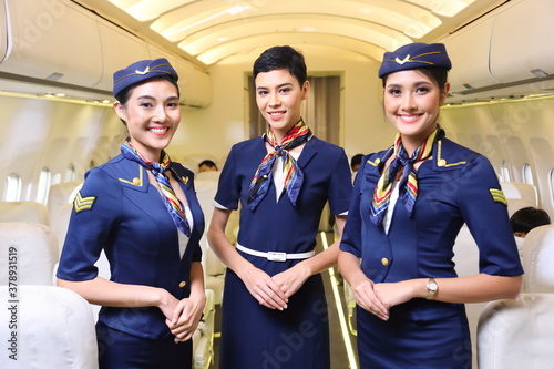 Tableau sur toile Team of diverse flight attendant posing with smile at middle of the aisle inside