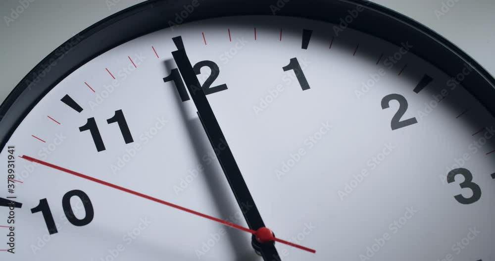 Closeup shot of a wall clock with hands moving in slow motion.