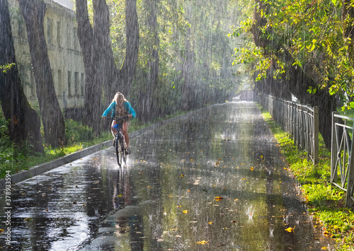 A cyclist rides along the Park alley in the pouring rain.