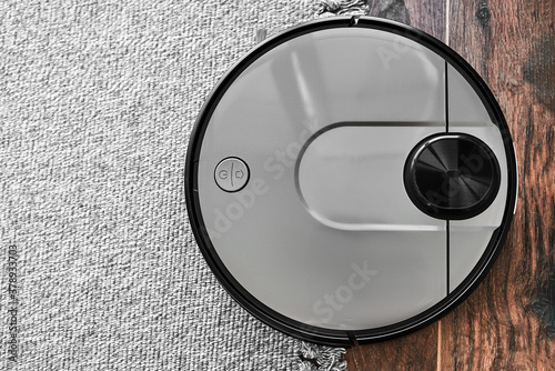 Top view of Robot vacuum cleaner on the edge of carpet and wooden floor. Close up with copy space