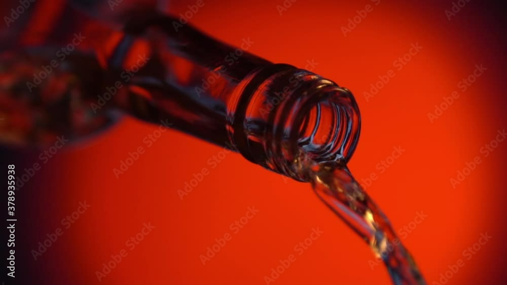 Cinemagraph of wine or alcohol pouring from bottle on red background. Seamless looping close up shot