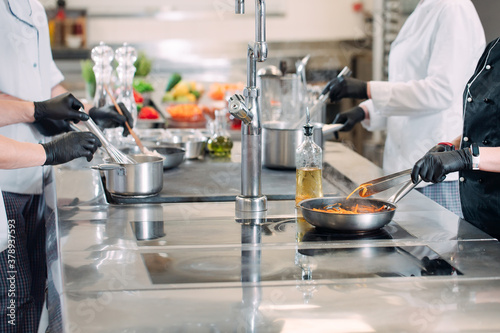Cooks prepare meals on an electric stove in a professional kitchen in a restaurant or hotel.