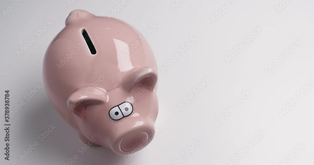 A Caucasian woman puts coins in a piggy bank.