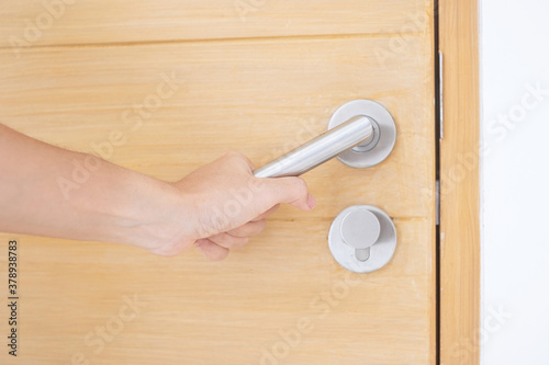 Closeup man holding handle doorknob of wooden door between open or close the door photo