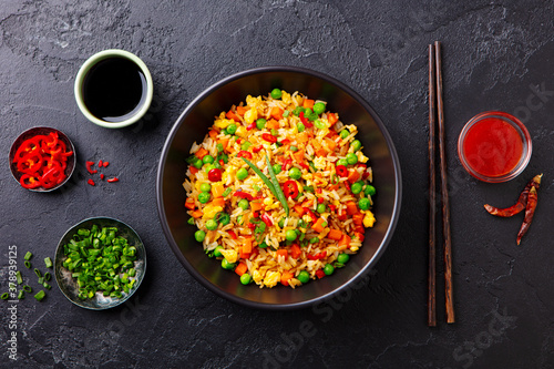 Asian fried rice with egg and vegetables. Dark slate background. Top view.