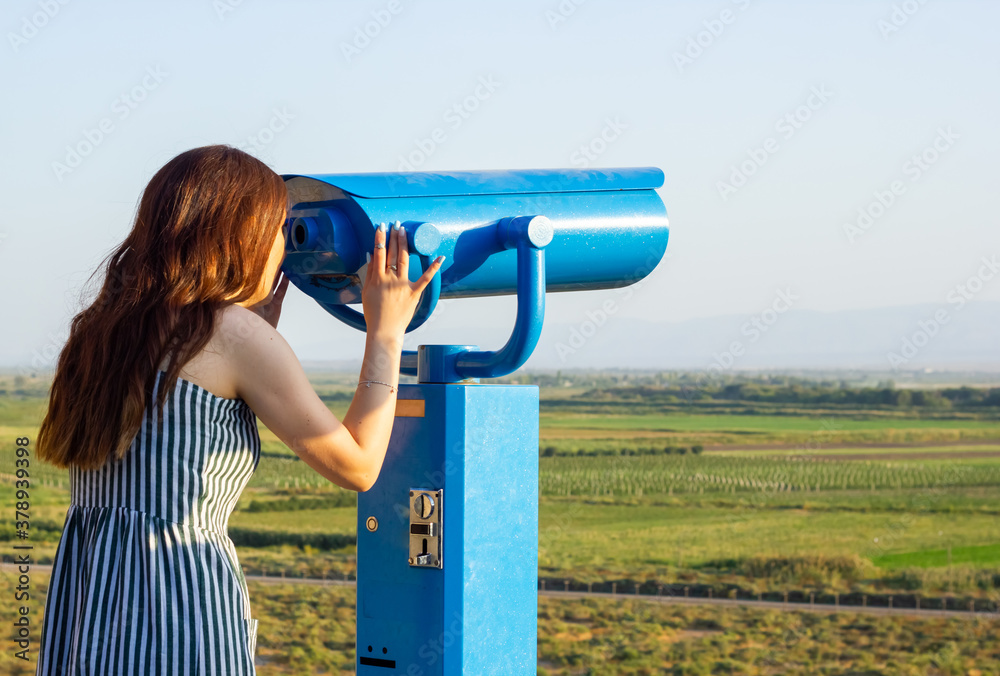 the young woman looking through binoculars