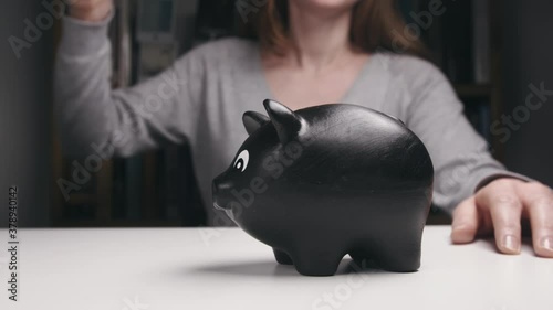 Slow motion shot of a Caucasian woman breaking a piggy bank and collecting the coins.