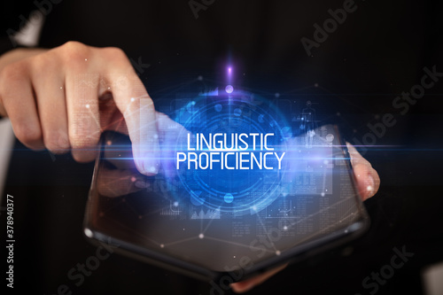 Young man holding a foldable smartphone with LINGUISTIC PROFICIENCY inscription, educational concept