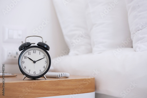 Black Retro alarm clock on table in bedroom at night, sleeping and daily routine concept