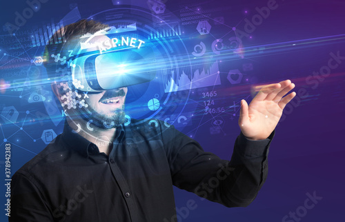 Businessman looking through Virtual Reality glasses with ASP.NET inscription, innovative technology concept