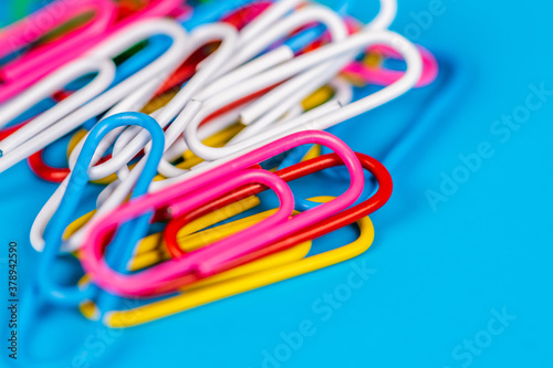 Heap of colorful paper clips with blurred blue background