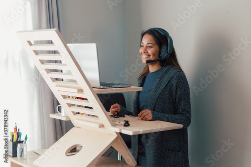 Young woman working on laptop at standing desk with earphones photo