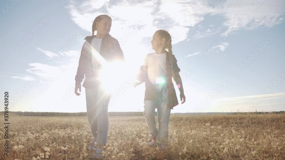 children walking in the park holding hands. kid dream happy family concept. children walking in nature outdoors sunlight. two sisters are walking together. kid fun with girlfriend holding hands dream