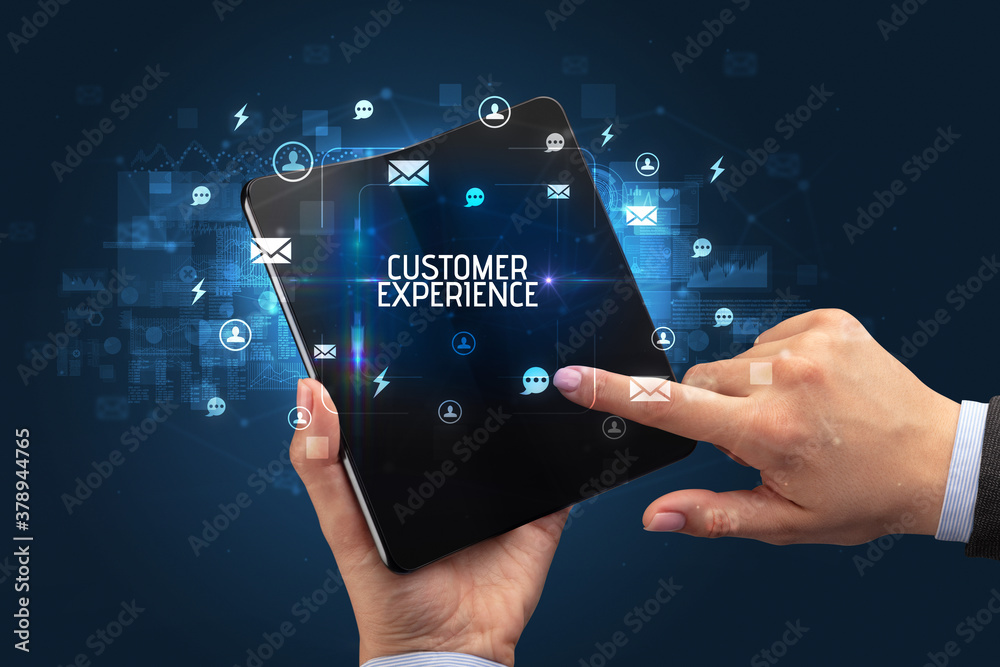 Businessman holding a foldable smartphone with CUSTOMER EXPERIENCE inscription, social networking concept Businessman holding a foldable smartphone with CUSTOMER EXPERIENCE inscription, social networking concept