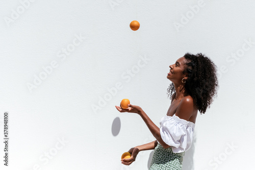 Cheerful black woman with fresh oranges