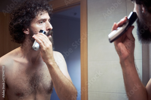 Middle-aged hispanic man cutting his beard