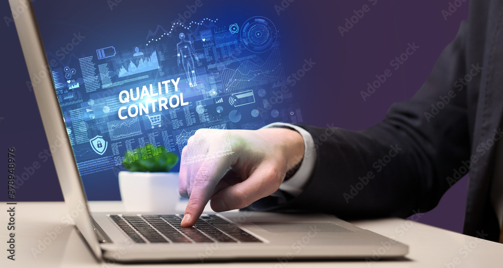 Businessman working on laptop with QUALITY CONTROL inscription, cyber technology concept Businessman working on laptop with QUALITY CONTROL inscription, cyber technology concept