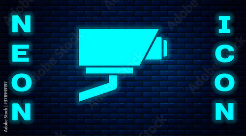 Glowing neon Security camera icon isolated on brick wall background. Vector.