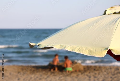 defocused children play by the sea and the big umbrella