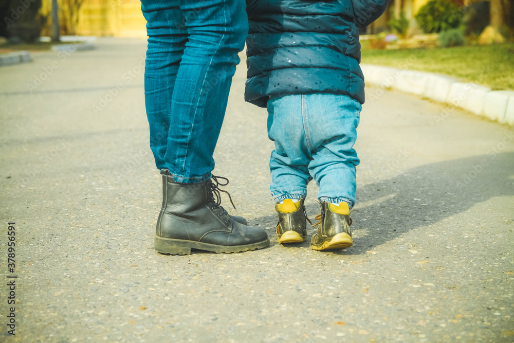 Mother teaches a little girl to walk. The child is holding his mother's hands. Mother teaches a little girl to walk. The child is holding his mother's hands.