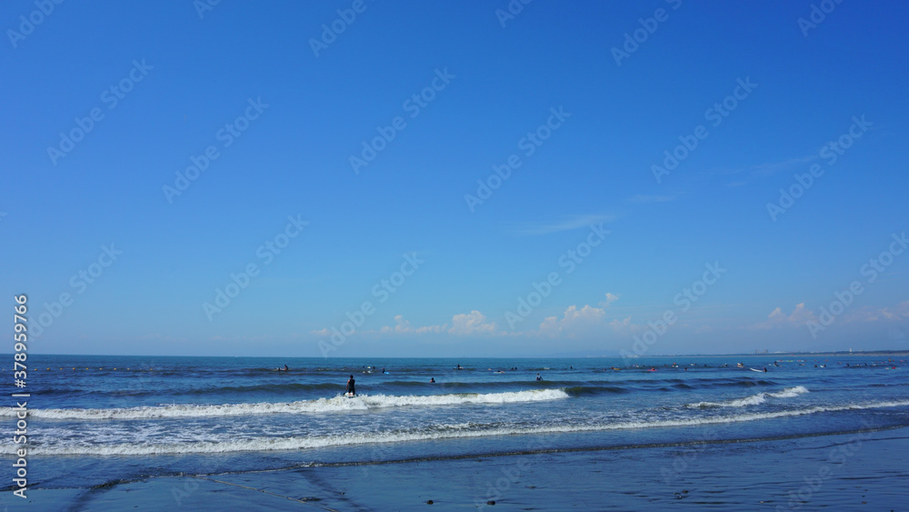 People surfing on sea waves under blue sky. Katase Nishihama beach is one of Japan's most popular beaches
