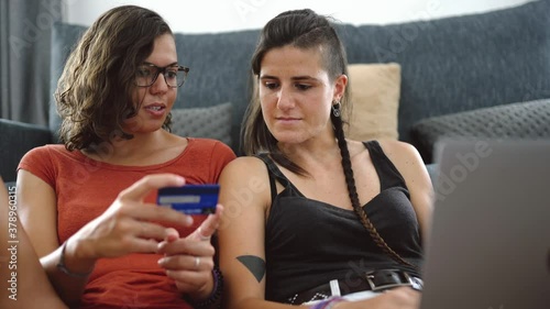 A couple of two lesbian girls make a card purchase online with the computer