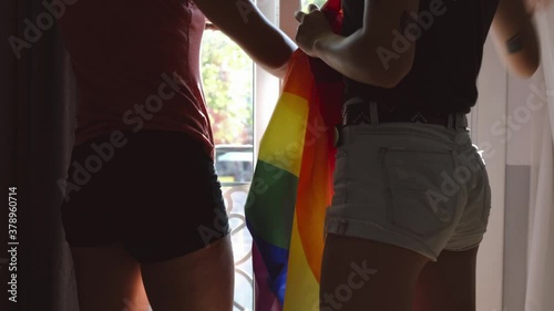 A couple of two lesbian girls with the LGBT flag in the window