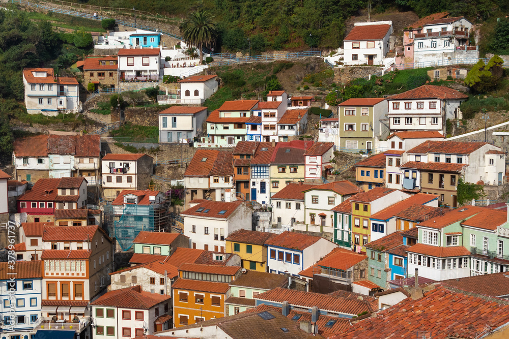 Panoramic picture of white houses and colorful houses built on the hill. Vertical town, narrow streets. Traditional red and orange roofs on top of the houses. Cudillero, Asturias, North of Spain