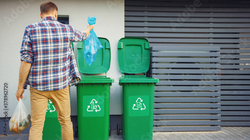 Wallpaper Mural Caucasian Man is Throwing Away Two Plastic Bags of Trash next to His House. One Garbage Bag is Sorted with Biological Food Waste, Other with Recyclable Bottles Garbage Bin. Torontodigital.ca
