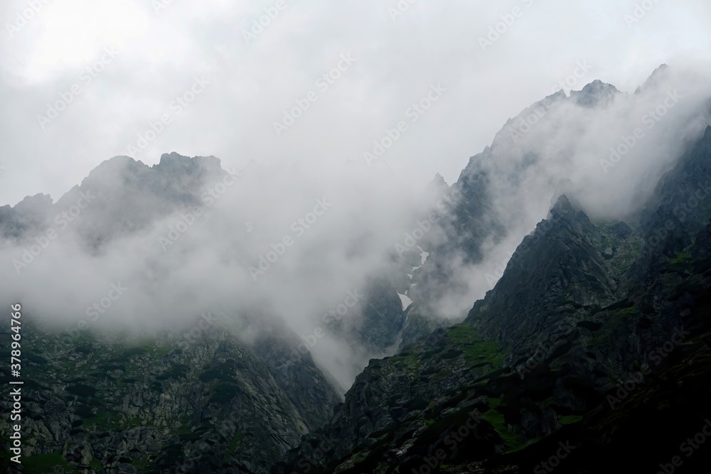 
The peaks of the High Tatras with white clouds. Mountains in the clouds. High Tatras Mountains in Slovakia