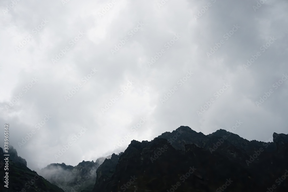 
The peaks of the High Tatras with white clouds. Mountains in the clouds. High Tatras Mountains in Slovakia