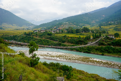 Bhutan, in Punakha, longest bridge in Bhutan crossing the river. In the background a typical village.